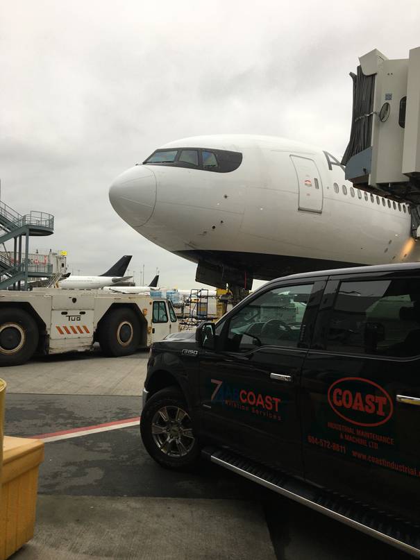 Coast Industrial vehicle on the airside ramp beside an aircraft